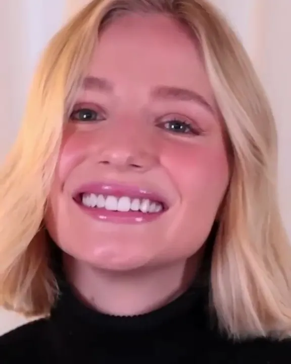 A smiling woman with a blonde bob and a black turtleneck