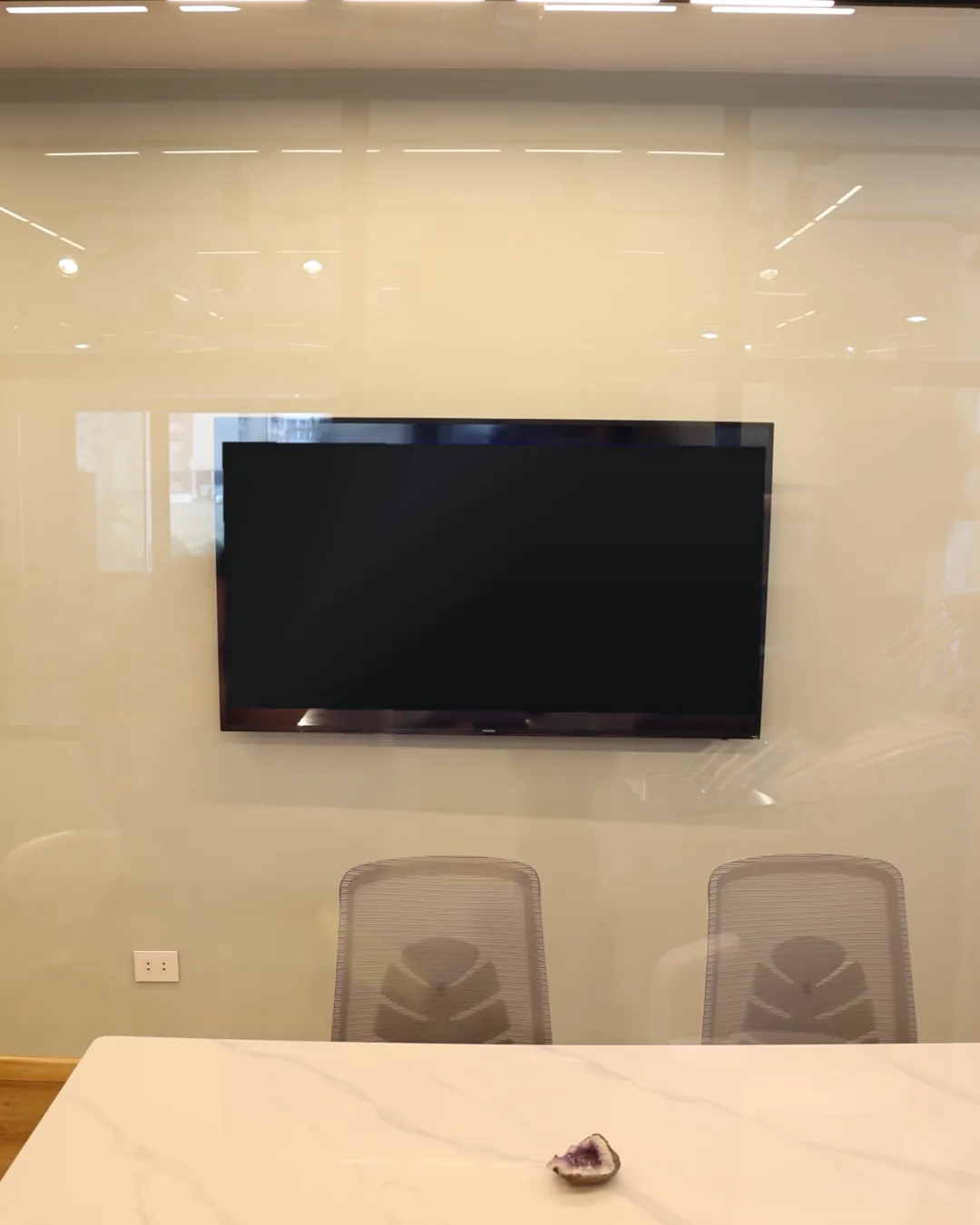 A screen on the consultation room wall, above the marble table