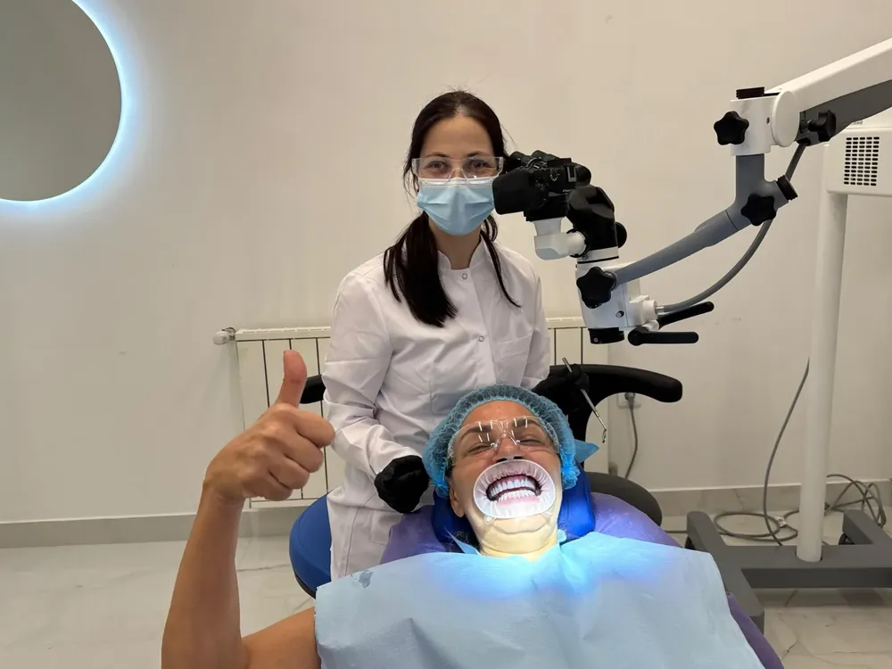 Dr. Milena Ilieva at the operating microscope, her patient giving a thumbs up